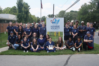 Lehigh Valley Humane Society employees displaying their plaque beside the shelter sign